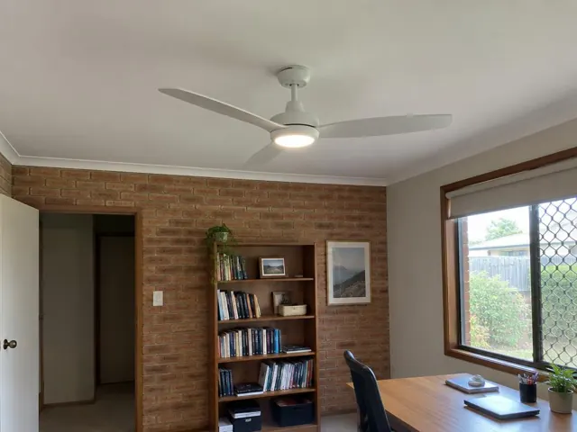 Ceiling fan on a white ceiling in a brick-walled home office with window and bookshelf in Rutherford